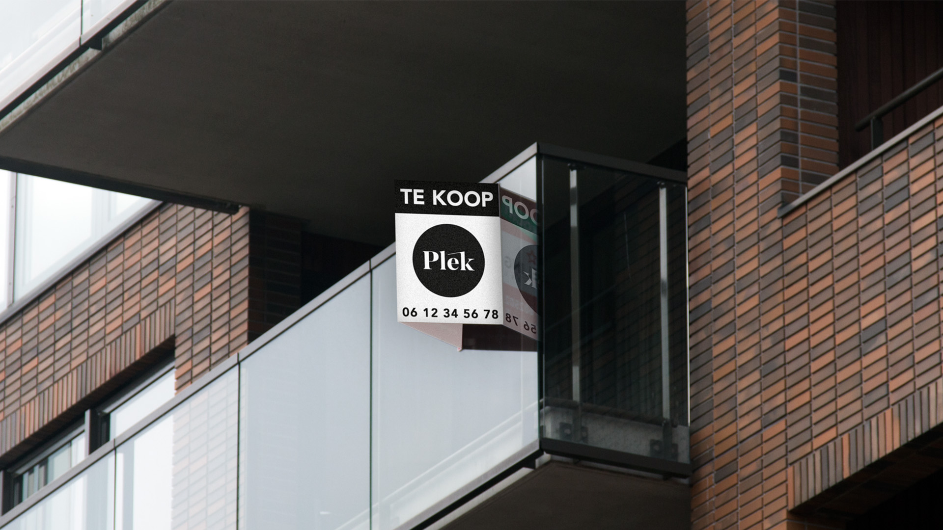 Een makelaarsbord aan een raam met de nieuwe Plek branding.